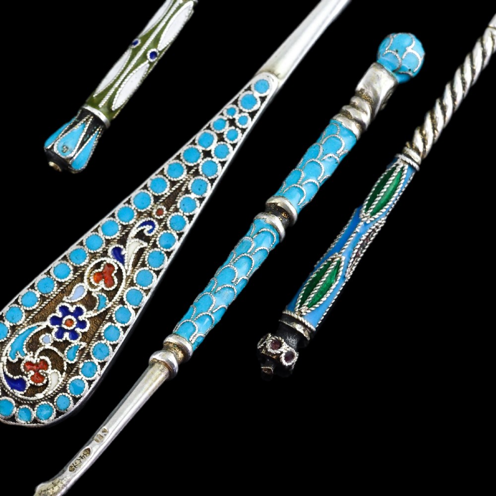 A four-piece set of late 19th-century Russian silver and cloisonne enamel cutlery featuring three spoons and a fork with turquoise blue, white, and red floral motifs. View V