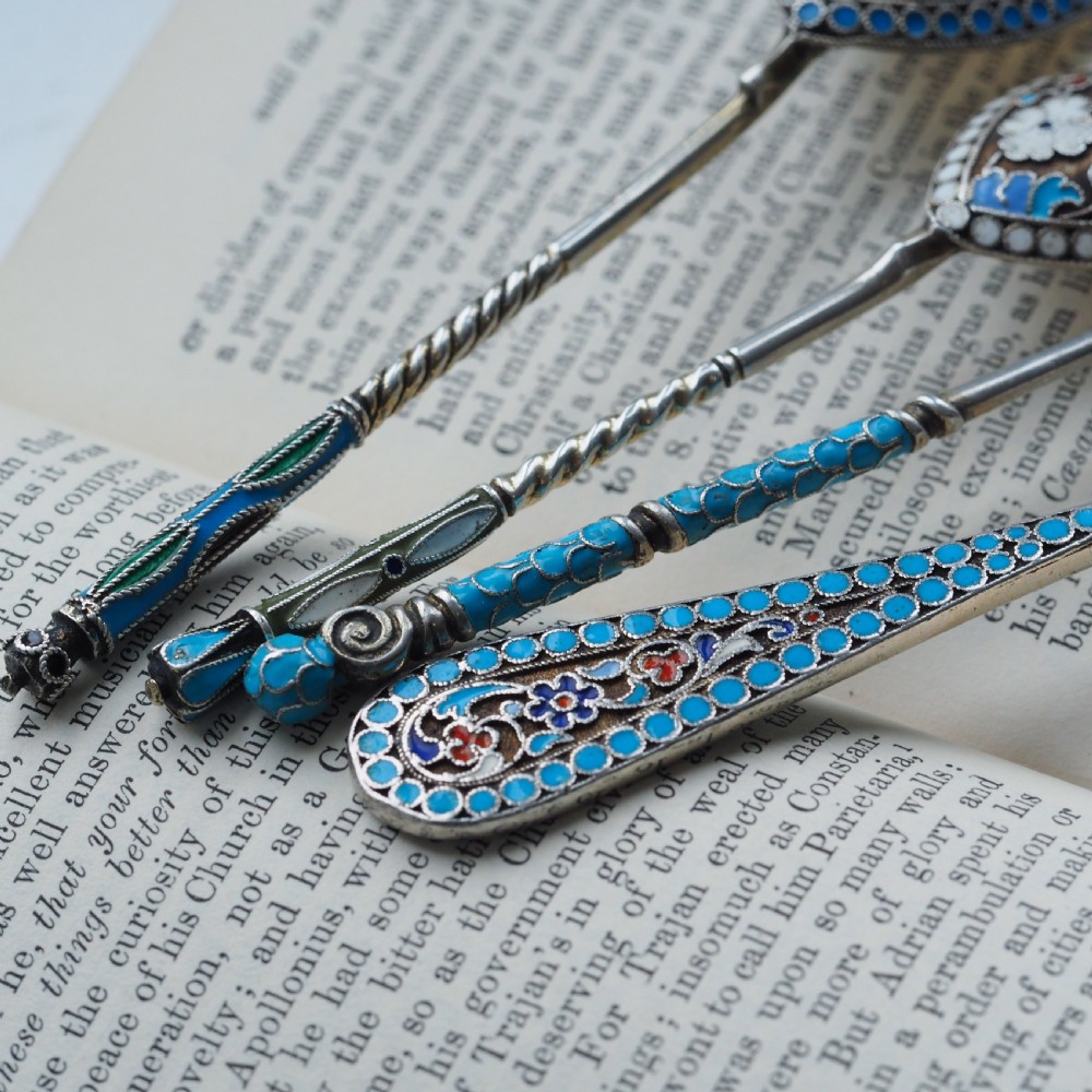 A four-piece set of late 19th-century Russian silver and cloisonne enamel cutlery featuring three spoons and a fork with turquoise blue, white, and red floral motifs. View X