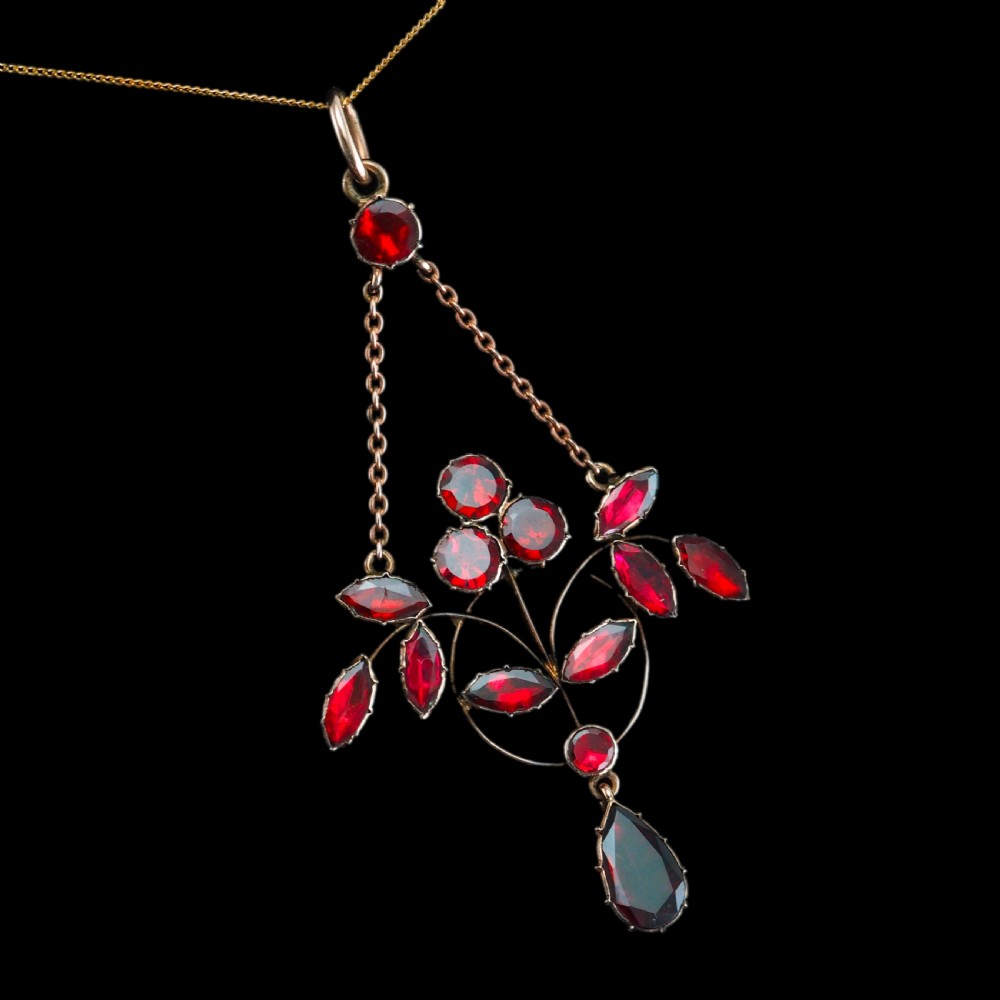 An Art Nouveau 9ct gold pendant necklace featuring marquise and round cut deep red garnets arranged in a foliate motif with a teardrop drop stone. View II
