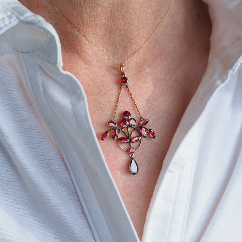 An Art Nouveau 9ct gold pendant necklace featuring marquise and round cut deep red garnets arranged in a foliate motif with a teardrop drop stone. View III