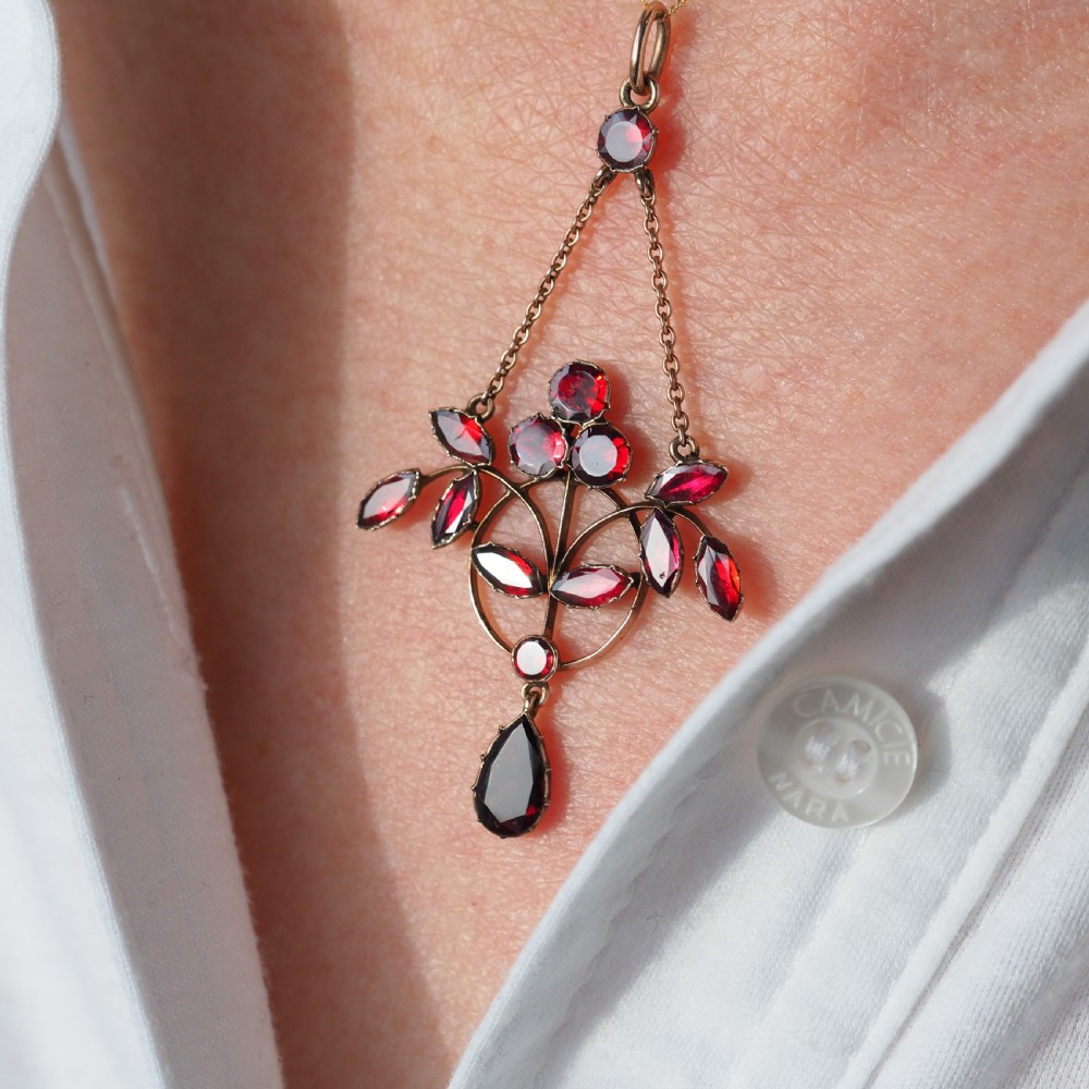 An Art Nouveau 9ct gold pendant necklace featuring marquise and round cut deep red garnets arranged in a foliate motif with a teardrop drop stone. View VIII