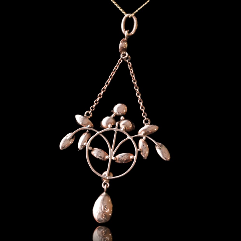 An Art Nouveau 9ct gold pendant necklace featuring marquise and round cut deep red garnets arranged in a foliate motif with a teardrop drop stone. View XVII