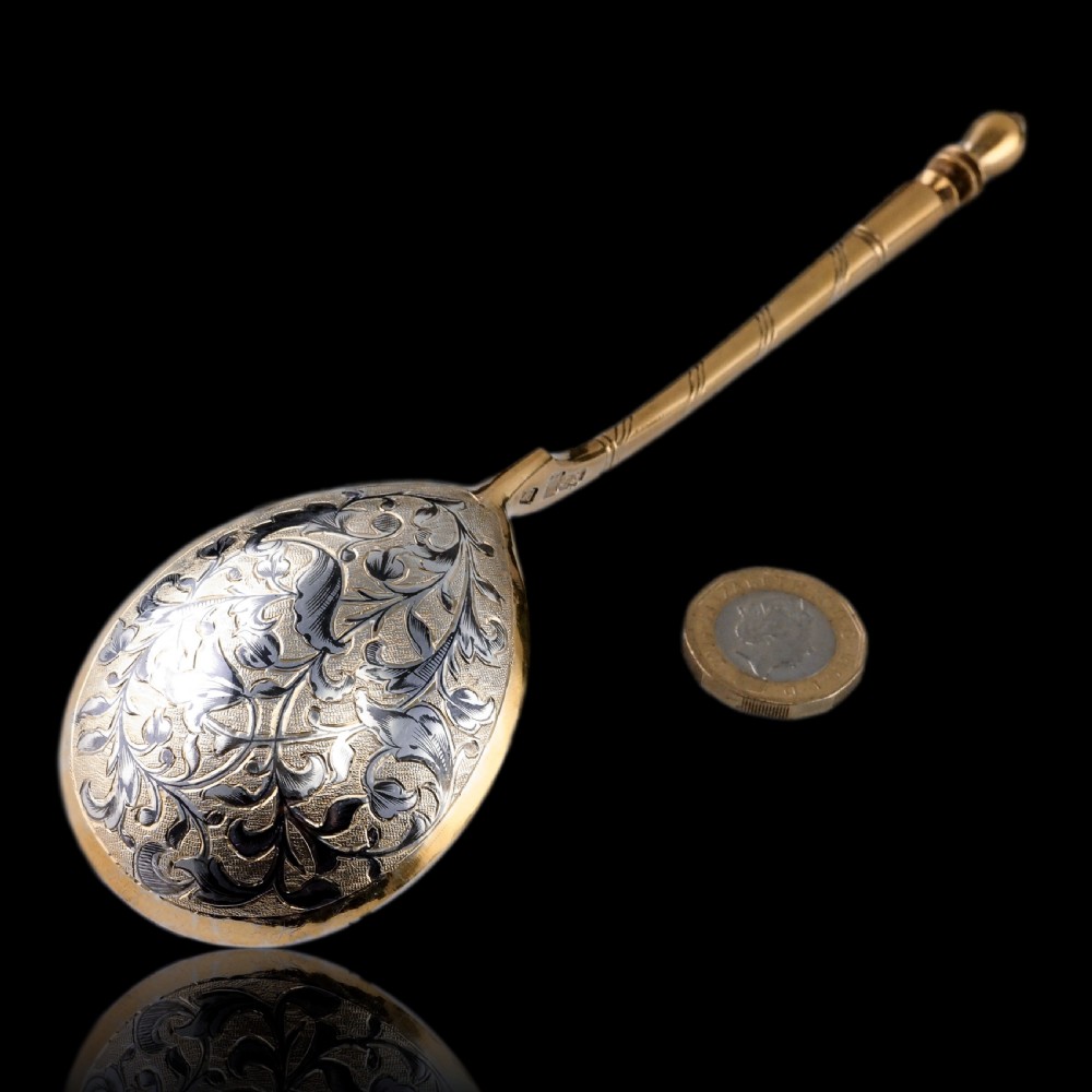 An antique Russian silver-gilt serving spoon featuring intricate black niello foliate engraving across the back of the oval bowl and a turned stem. View II