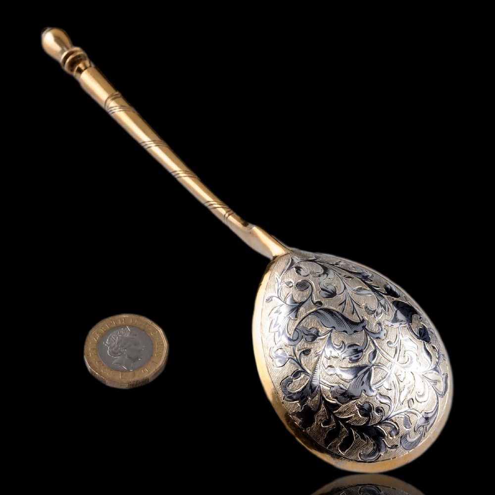 An antique Russian silver-gilt serving spoon featuring intricate black niello foliate engraving across the back of the oval bowl and a turned stem. View III