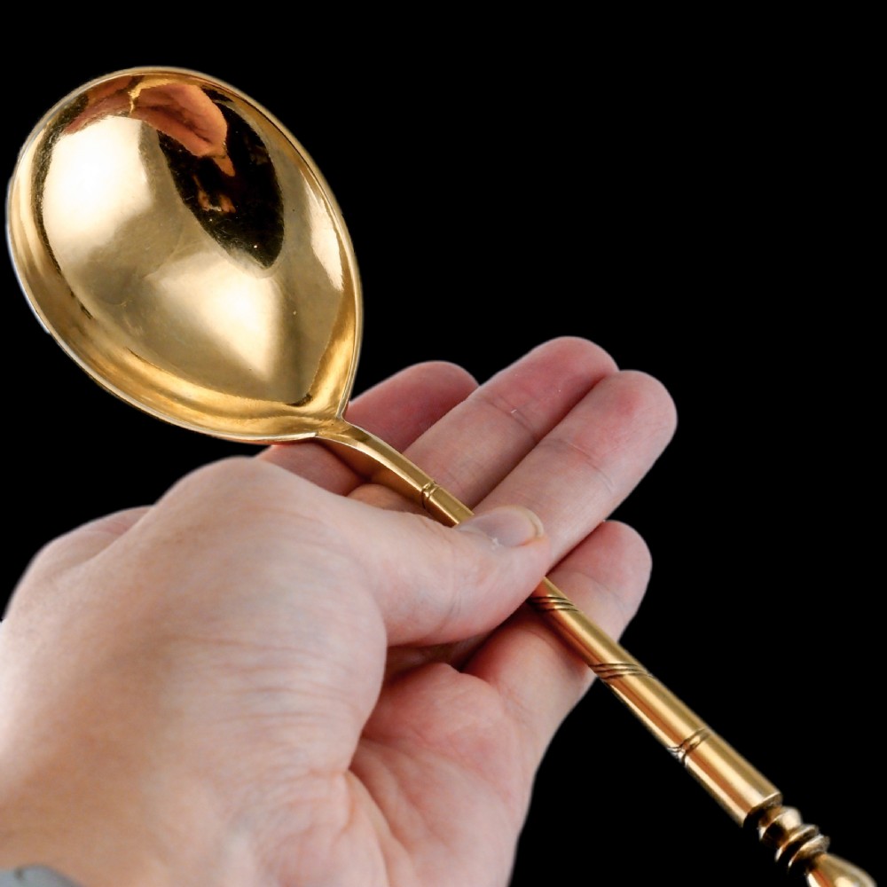 An antique Russian silver-gilt serving spoon featuring intricate black niello foliate engraving across the back of the oval bowl and a turned stem. View IV