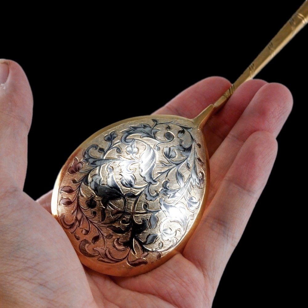 An antique Russian silver-gilt serving spoon featuring intricate black niello foliate engraving across the back of the oval bowl and a turned stem. View V