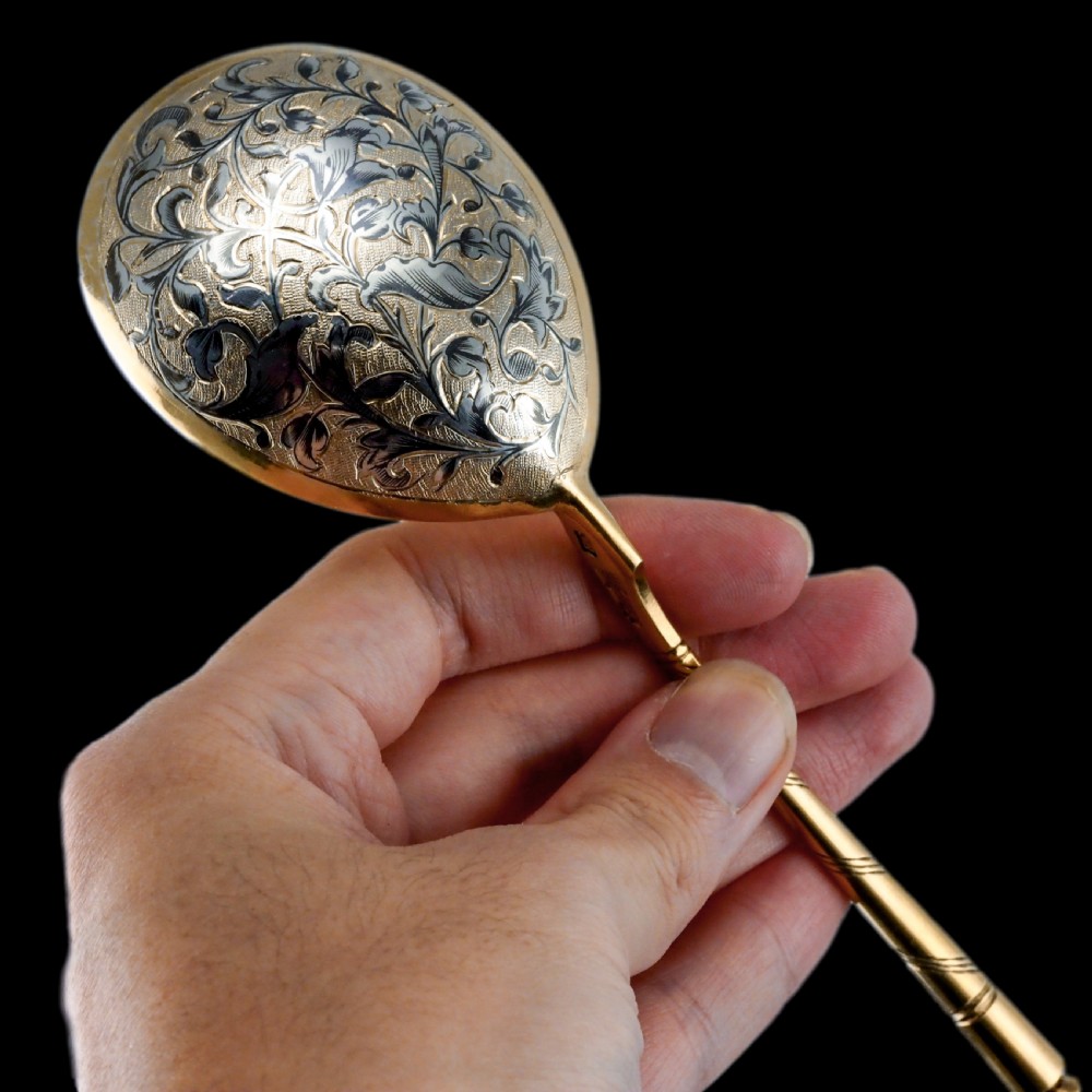 An antique Russian silver-gilt serving spoon featuring intricate black niello foliate engraving across the back of the oval bowl and a turned stem. View VII