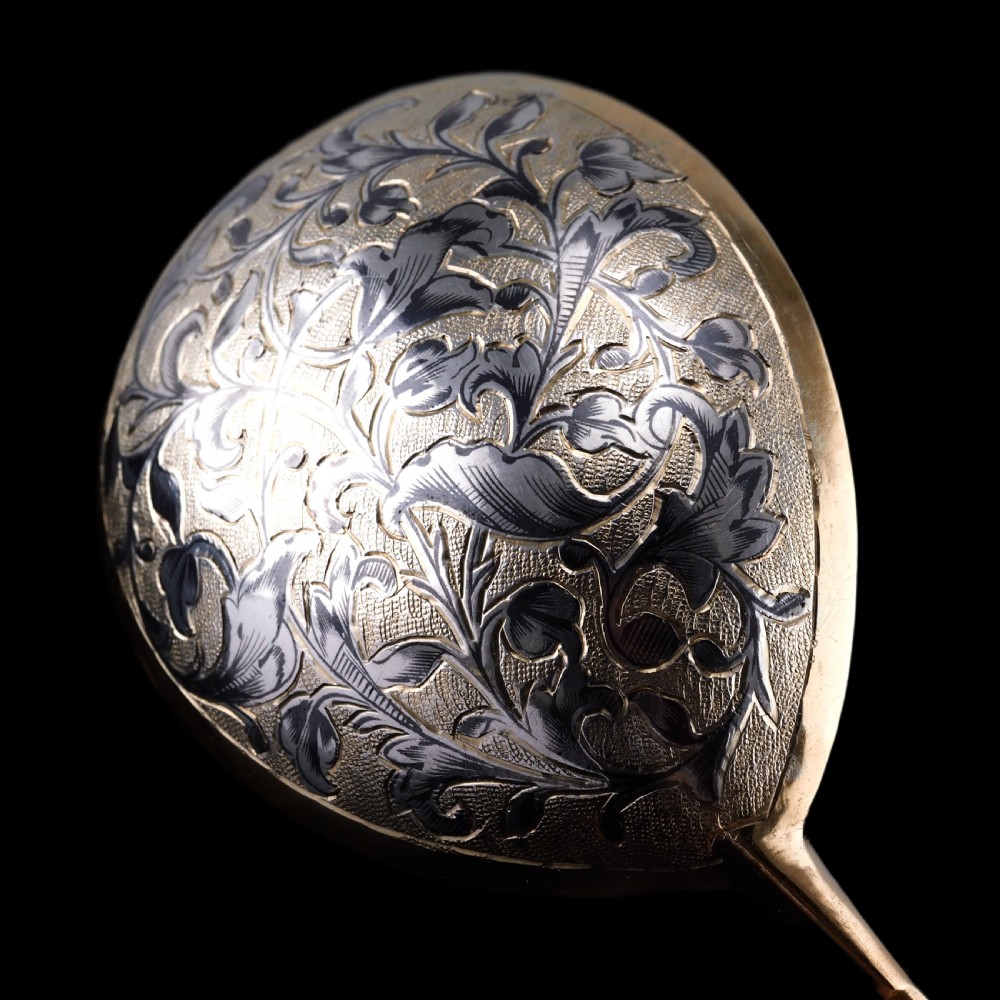 An antique Russian silver-gilt serving spoon featuring intricate black niello foliate engraving across the back of the oval bowl and a turned stem. View XII