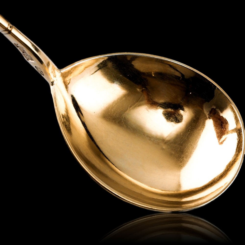 An antique Russian silver-gilt serving spoon featuring intricate black niello foliate engraving across the back of the oval bowl and a turned stem. View XV