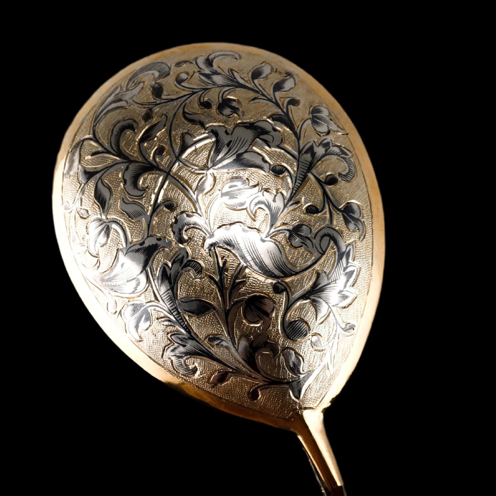 An antique Russian silver-gilt serving spoon featuring intricate black niello foliate engraving across the back of the oval bowl and a turned stem. View XVII