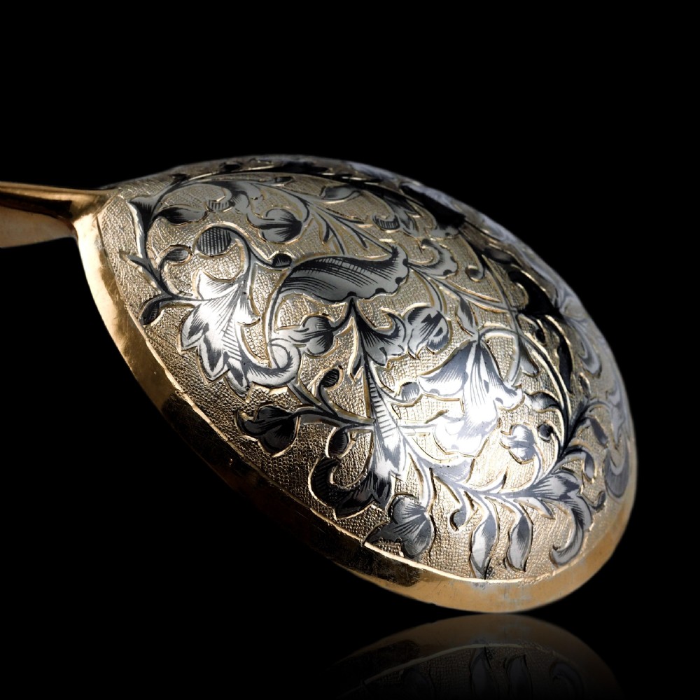 An antique Russian silver-gilt serving spoon featuring intricate black niello foliate engraving across the back of the oval bowl and a turned stem. View XIX