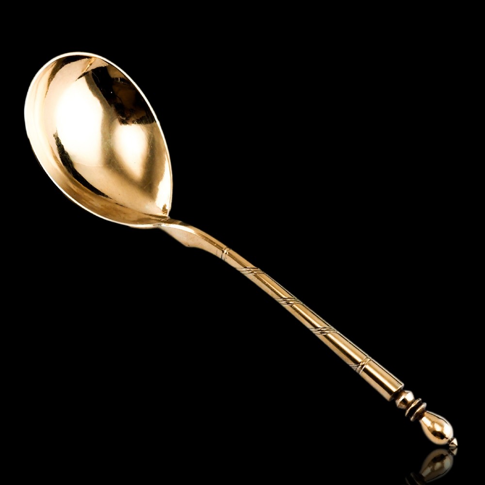 An antique Russian silver-gilt serving spoon featuring intricate black niello foliate engraving across the back of the oval bowl and a turned stem. View XXIII