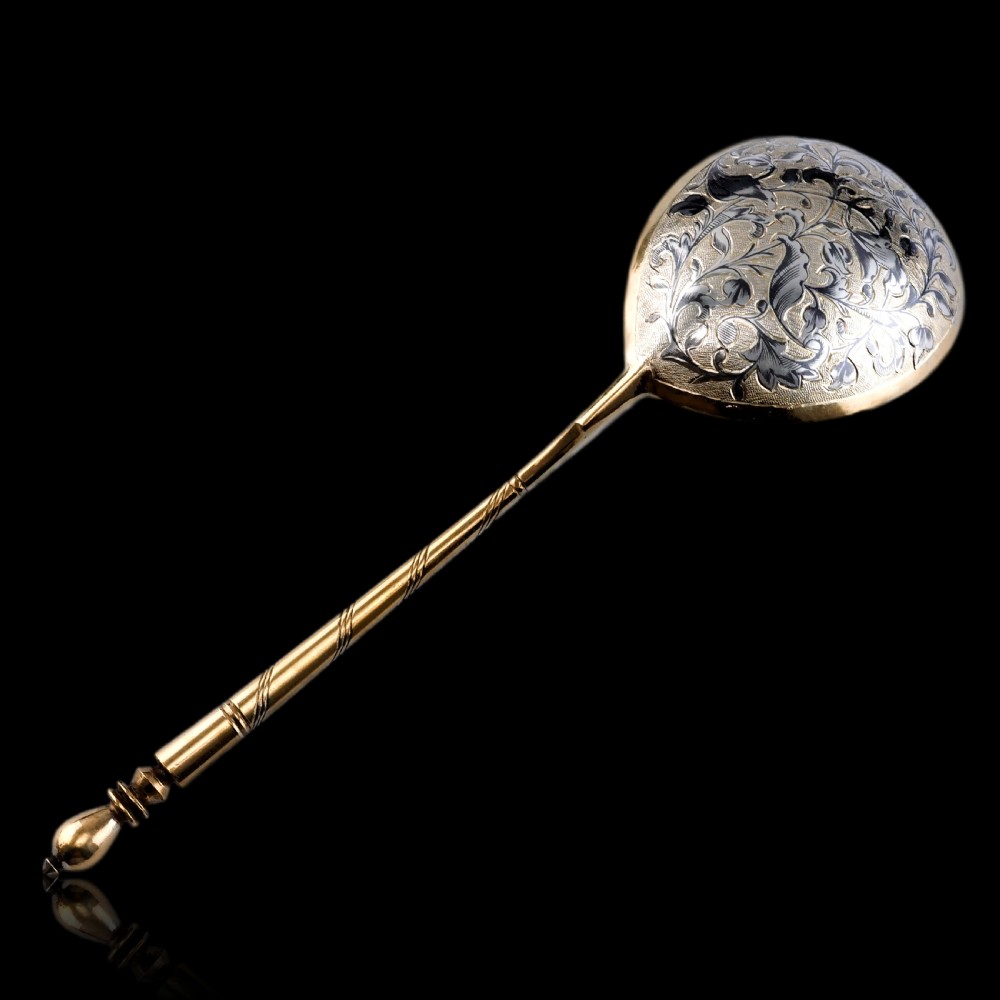 An antique Russian silver-gilt serving spoon featuring intricate black niello foliate engraving across the back of the oval bowl and a turned stem. View XXIV