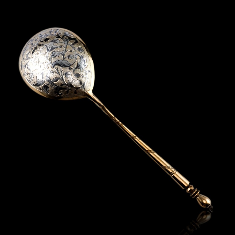 An antique Russian silver-gilt serving spoon featuring intricate black niello foliate engraving across the back of the oval bowl and a turned stem. View XXV