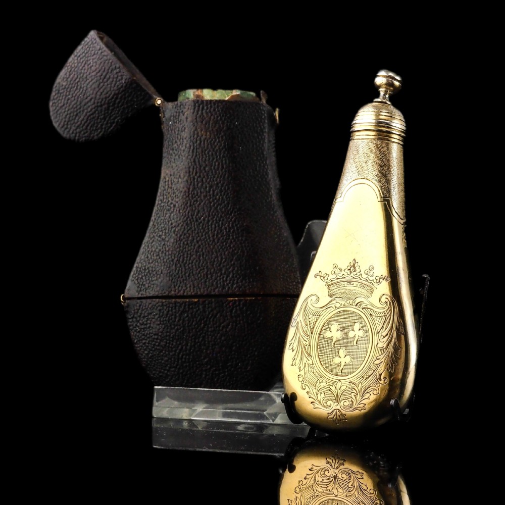 A seventeenth-century teardrop-shaped silver gilt scent flask engraved with a coronet and crest, positioned alongside its dark leather case. View III