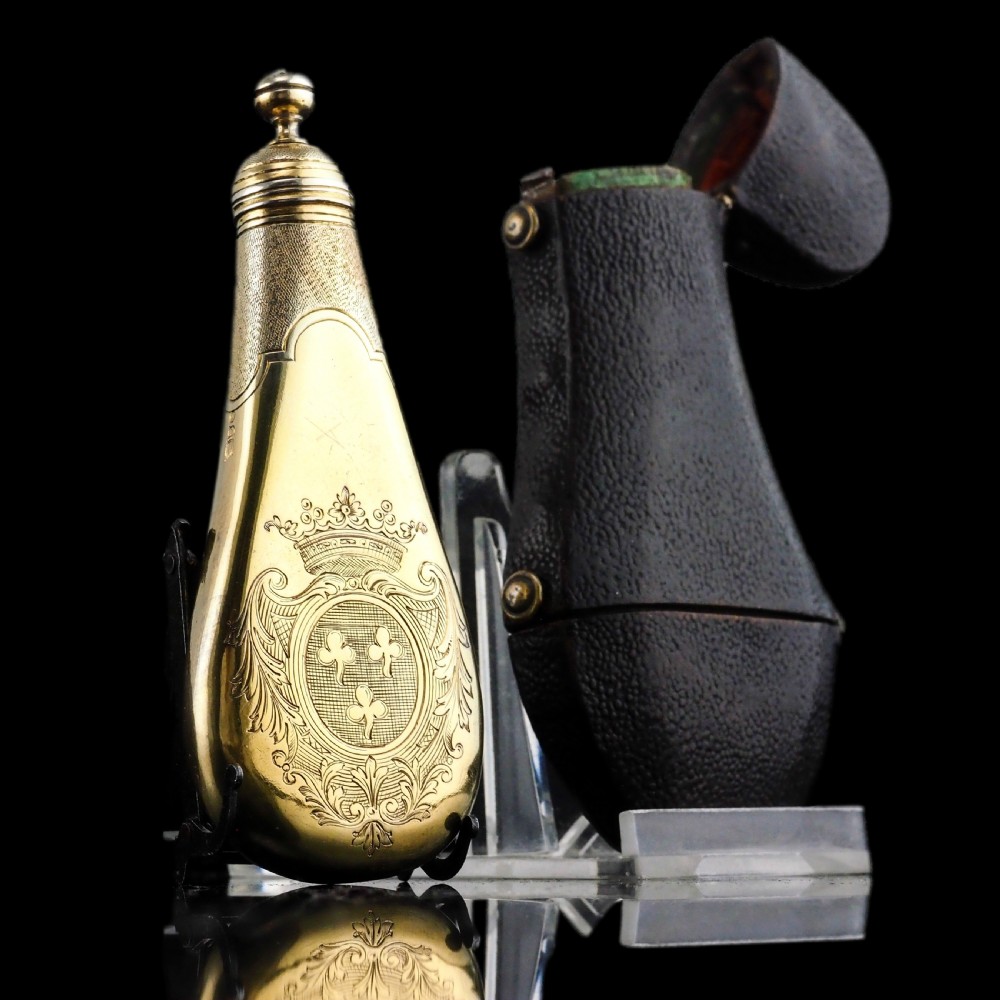 A seventeenth-century teardrop-shaped silver gilt scent flask engraved with a coronet and crest, positioned alongside its dark leather case. View IV