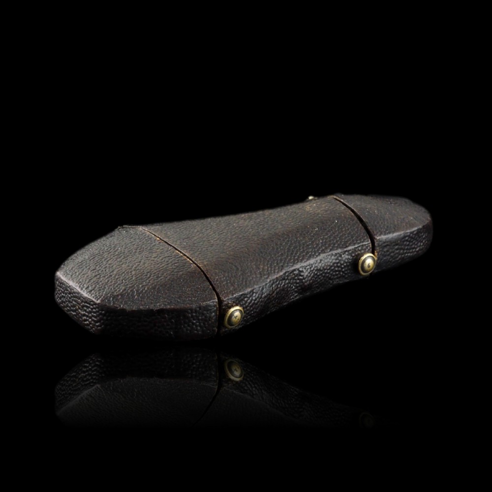 A seventeenth-century teardrop-shaped silver gilt scent flask engraved with a coronet and crest, positioned alongside its dark leather case. View V
