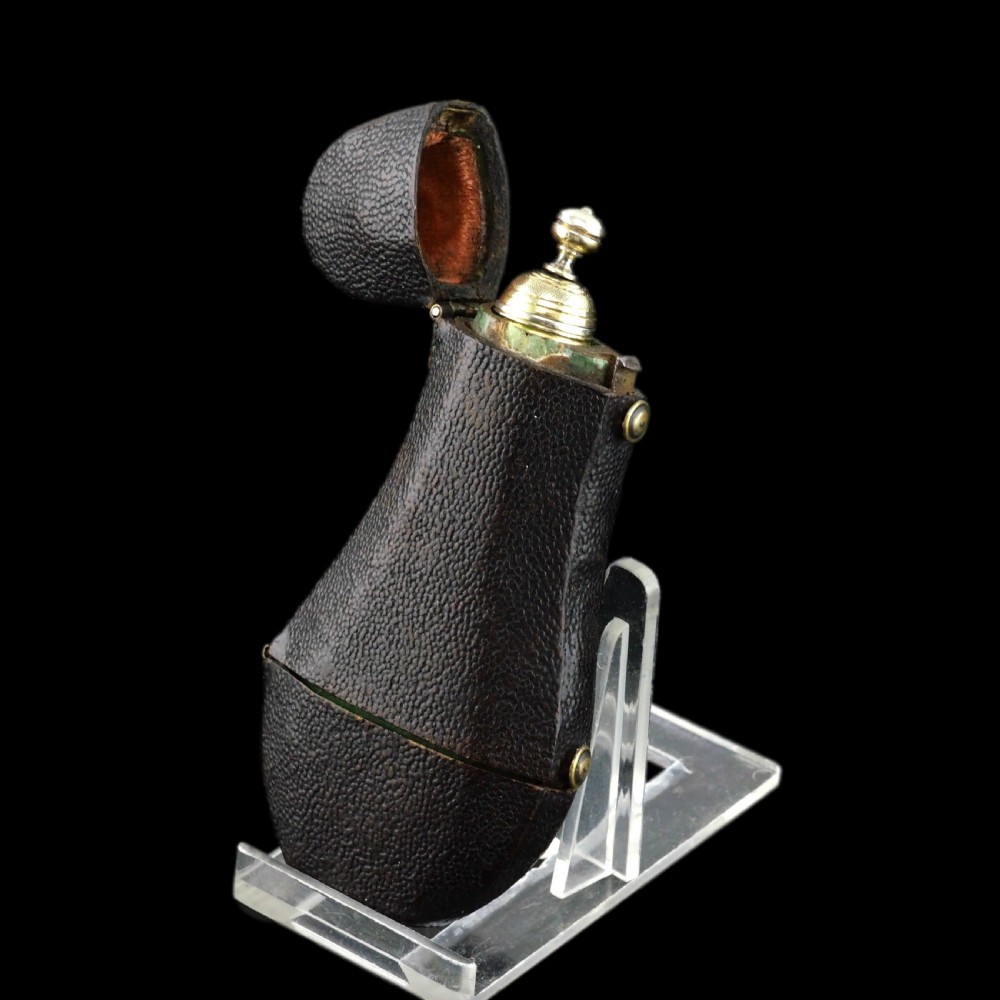 A seventeenth-century teardrop-shaped silver gilt scent flask engraved with a coronet and crest, positioned alongside its dark leather case. View VI