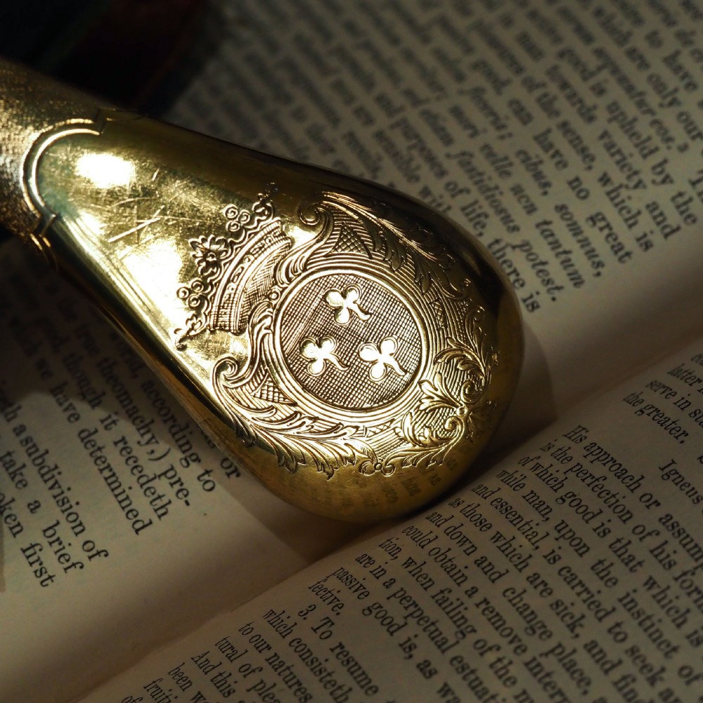 A seventeenth-century teardrop-shaped silver gilt scent flask engraved with a coronet and crest, positioned alongside its dark leather case. View XI
