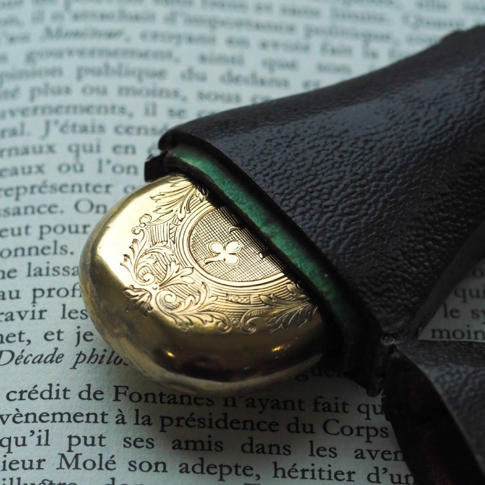 A seventeenth-century teardrop-shaped silver gilt scent flask engraved with a coronet and crest, positioned alongside its dark leather case. View XVIII