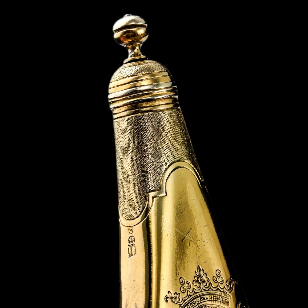 A seventeenth-century teardrop-shaped silver gilt scent flask engraved with a coronet and crest, positioned alongside its dark leather case. View XXII