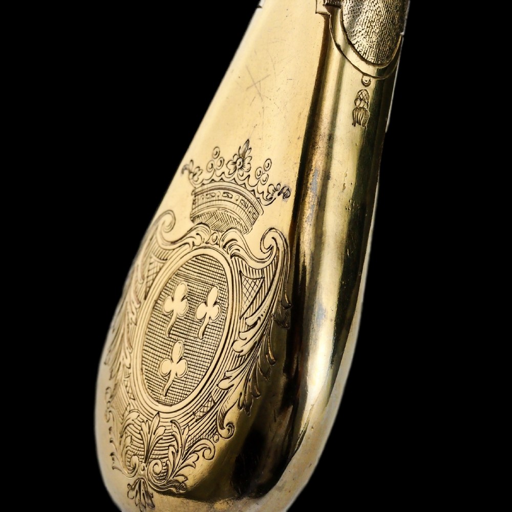 A seventeenth-century teardrop-shaped silver gilt scent flask engraved with a coronet and crest, positioned alongside its dark leather case. View XXIV