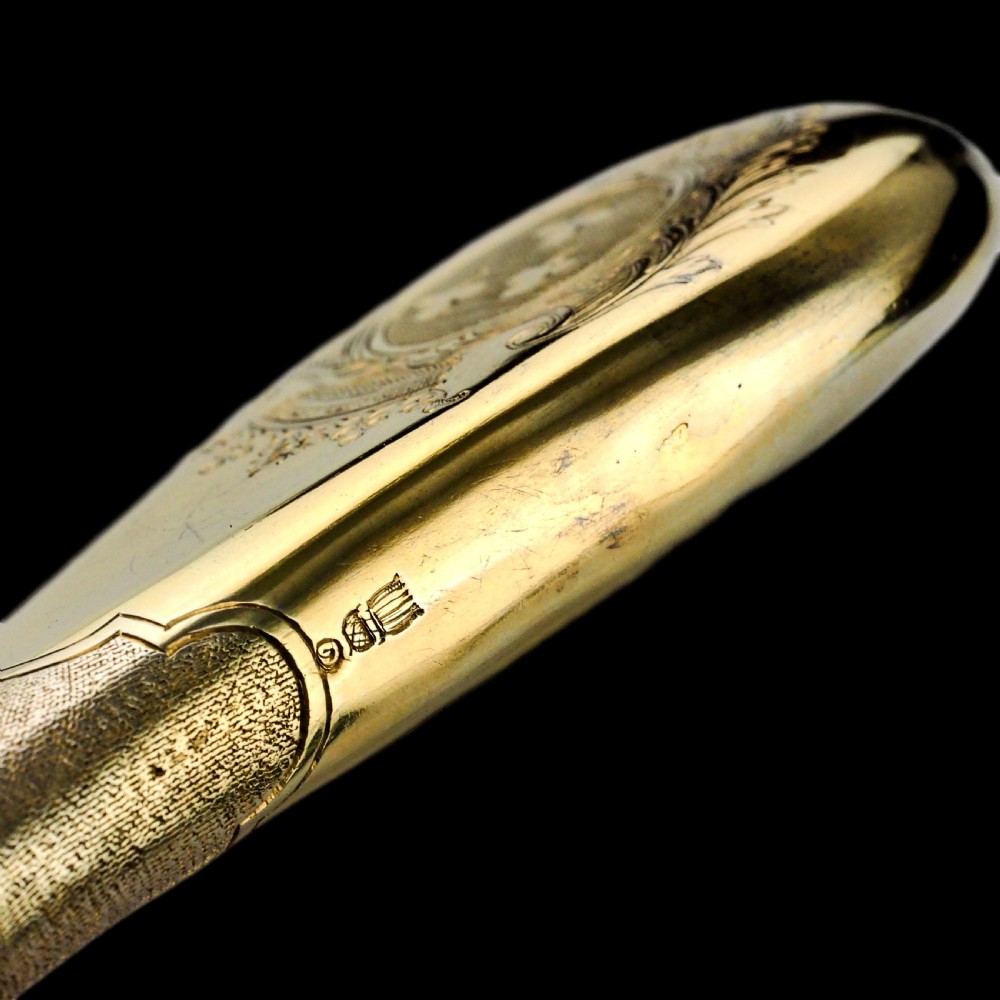A seventeenth-century teardrop-shaped silver gilt scent flask engraved with a coronet and crest, positioned alongside its dark leather case. View XXVI