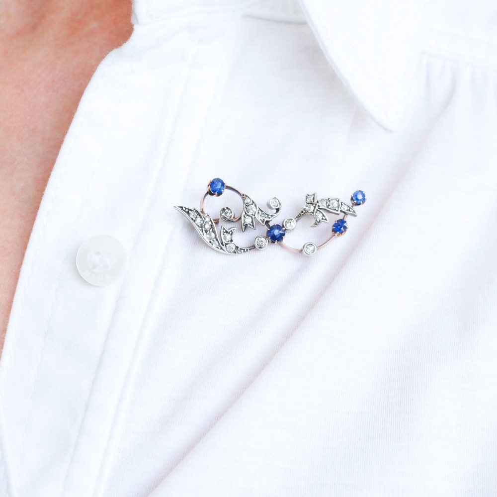 An antique Victorian foliate scroll brooch crafted in gold and silver, set with circular blue sapphires and accent diamonds. View II