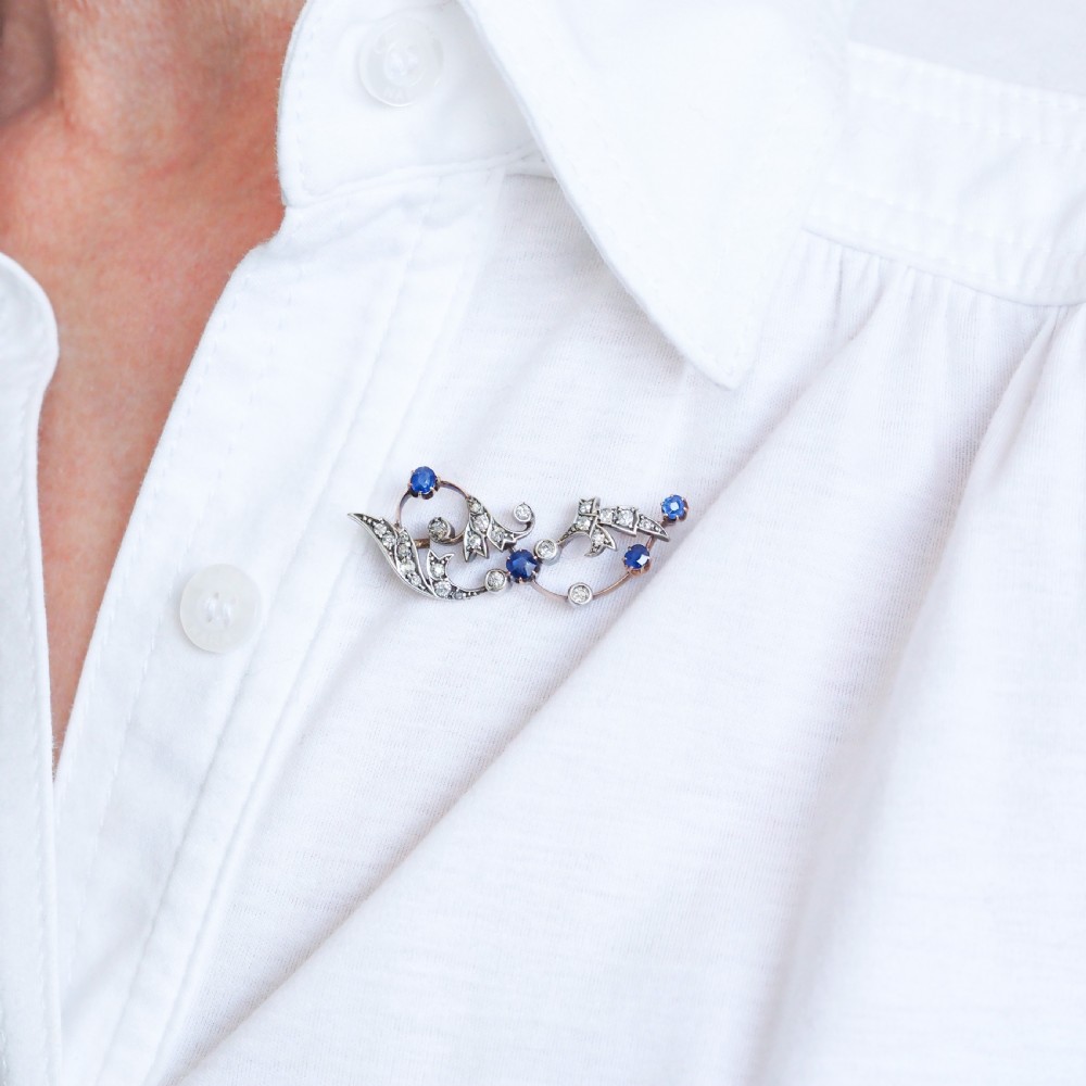An antique Victorian foliate scroll brooch crafted in gold and silver, set with circular blue sapphires and accent diamonds. View VIII