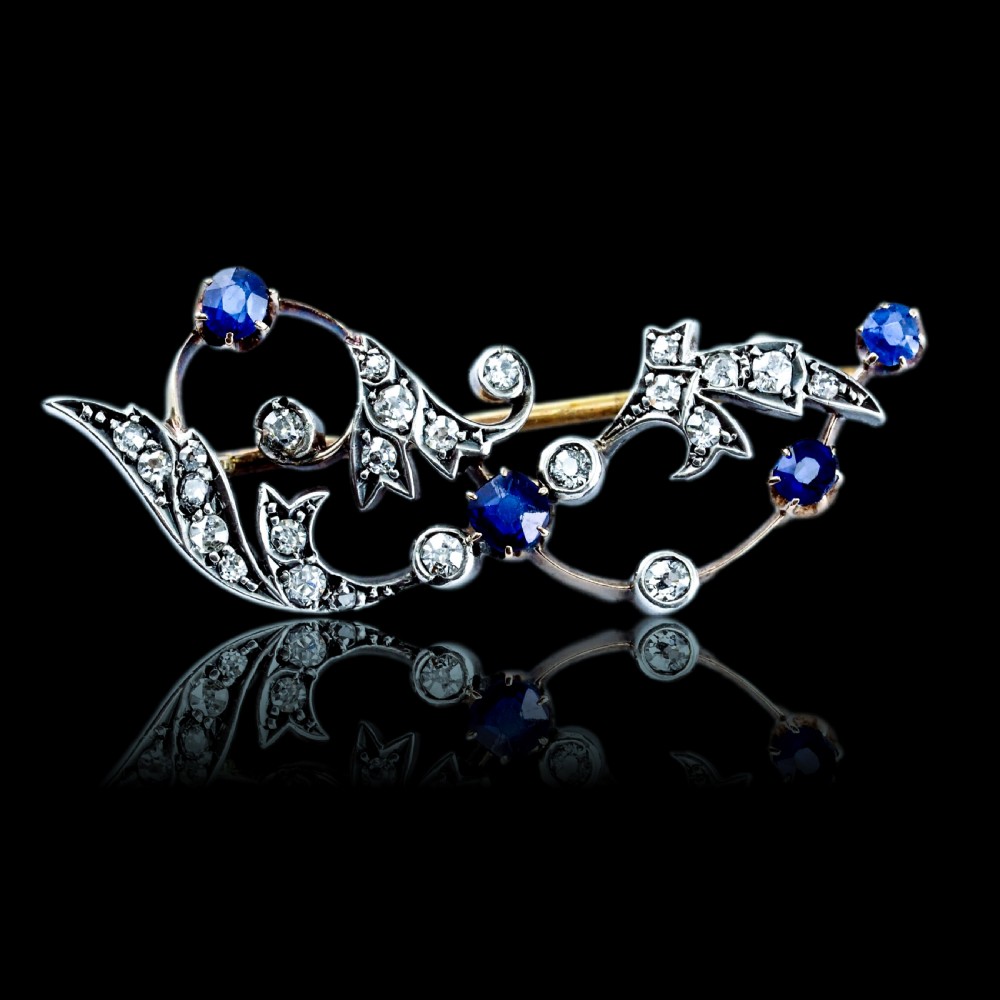An antique Victorian foliate scroll brooch crafted in gold and silver, set with circular blue sapphires and accent diamonds. View XIII