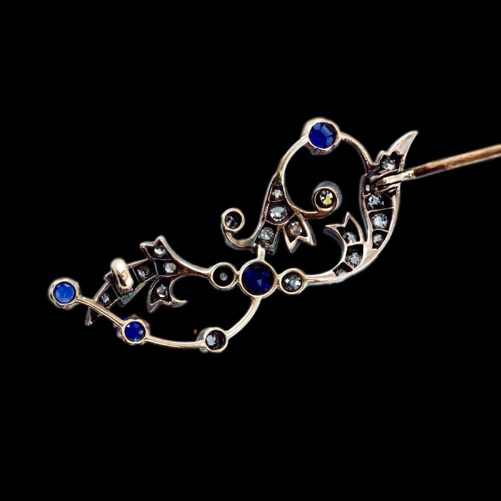 An antique Victorian foliate scroll brooch crafted in gold and silver, set with circular blue sapphires and accent diamonds. View XIV