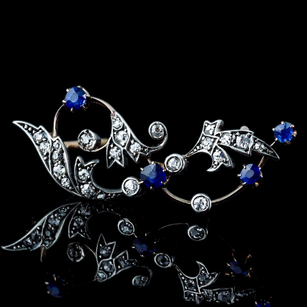 An antique Victorian foliate scroll brooch crafted in gold and silver, set with circular blue sapphires and accent diamonds. View XVII