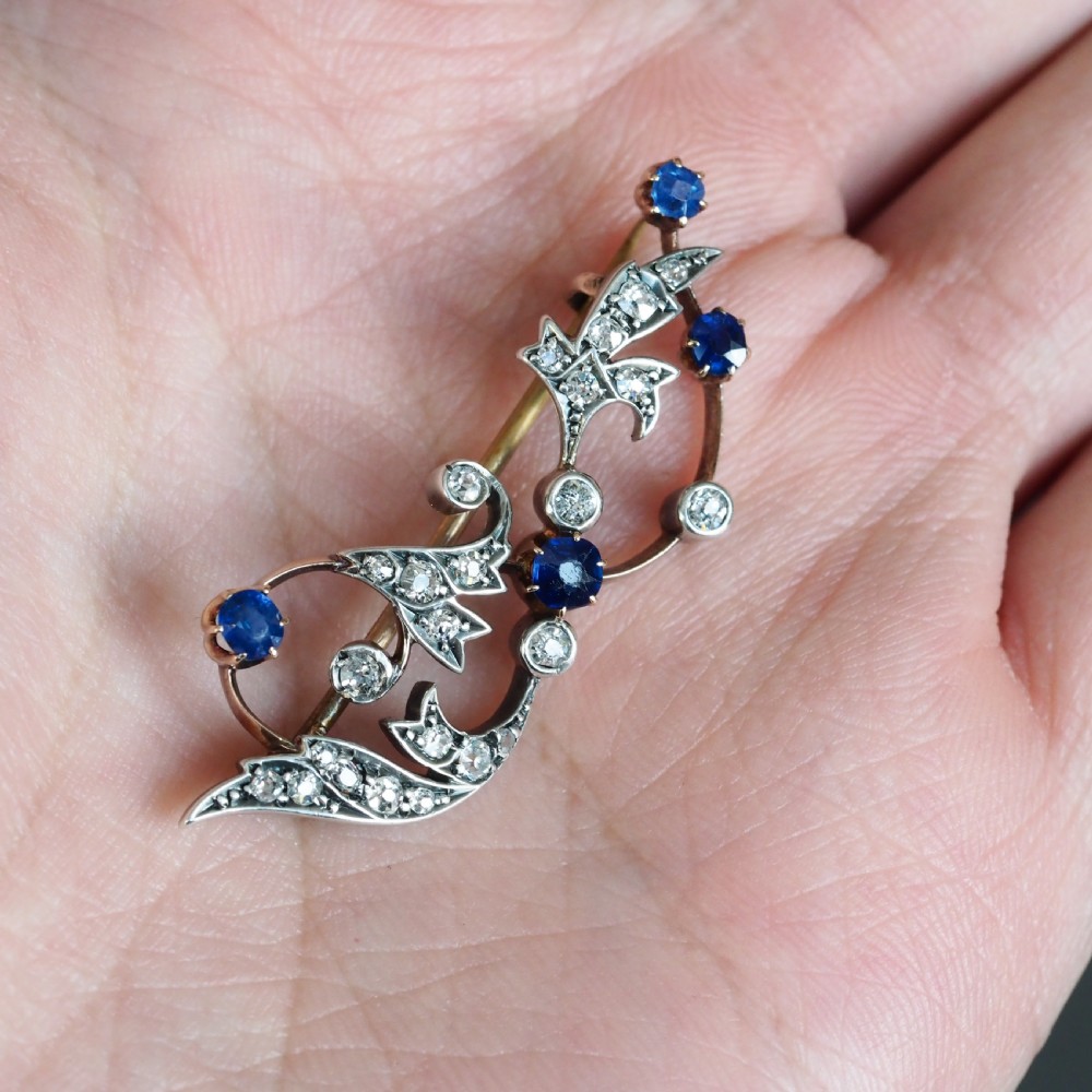 An antique Victorian foliate scroll brooch crafted in gold and silver, set with circular blue sapphires and accent diamonds. View XXII