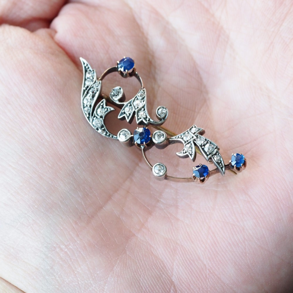 An antique Victorian foliate scroll brooch crafted in gold and silver, set with circular blue sapphires and accent diamonds. View XXIII