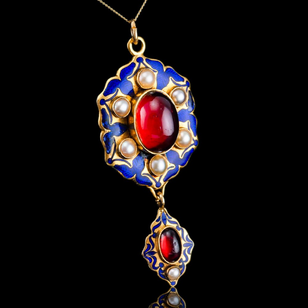 An 18k yellow gold Victorian Holbeinesque pendant featuring a central red cabochon garnet surrounded by pearls, blue enamel, and an articulated gemstone drop.