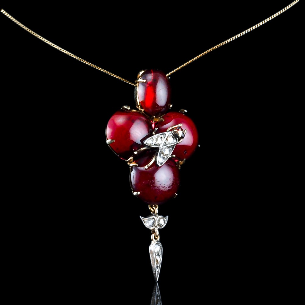 Victorian gold brooch pendant set with four deep red cabochon garnets, a diamond-encrusted insect motif at the centre, and an articulated diamond drop. View IV