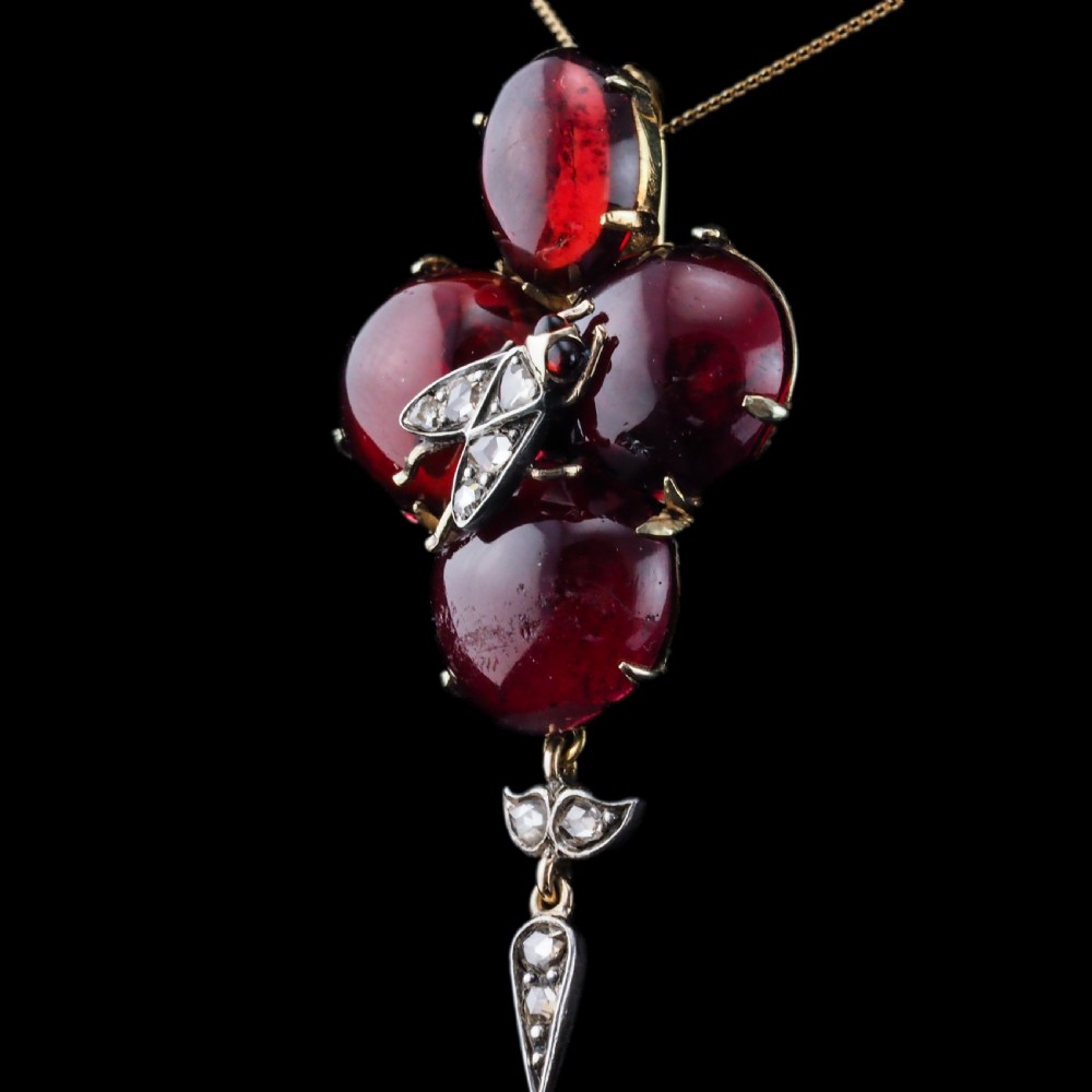 Victorian gold brooch pendant set with four deep red cabochon garnets, a diamond-encrusted insect motif at the centre, and an articulated diamond drop. View VI