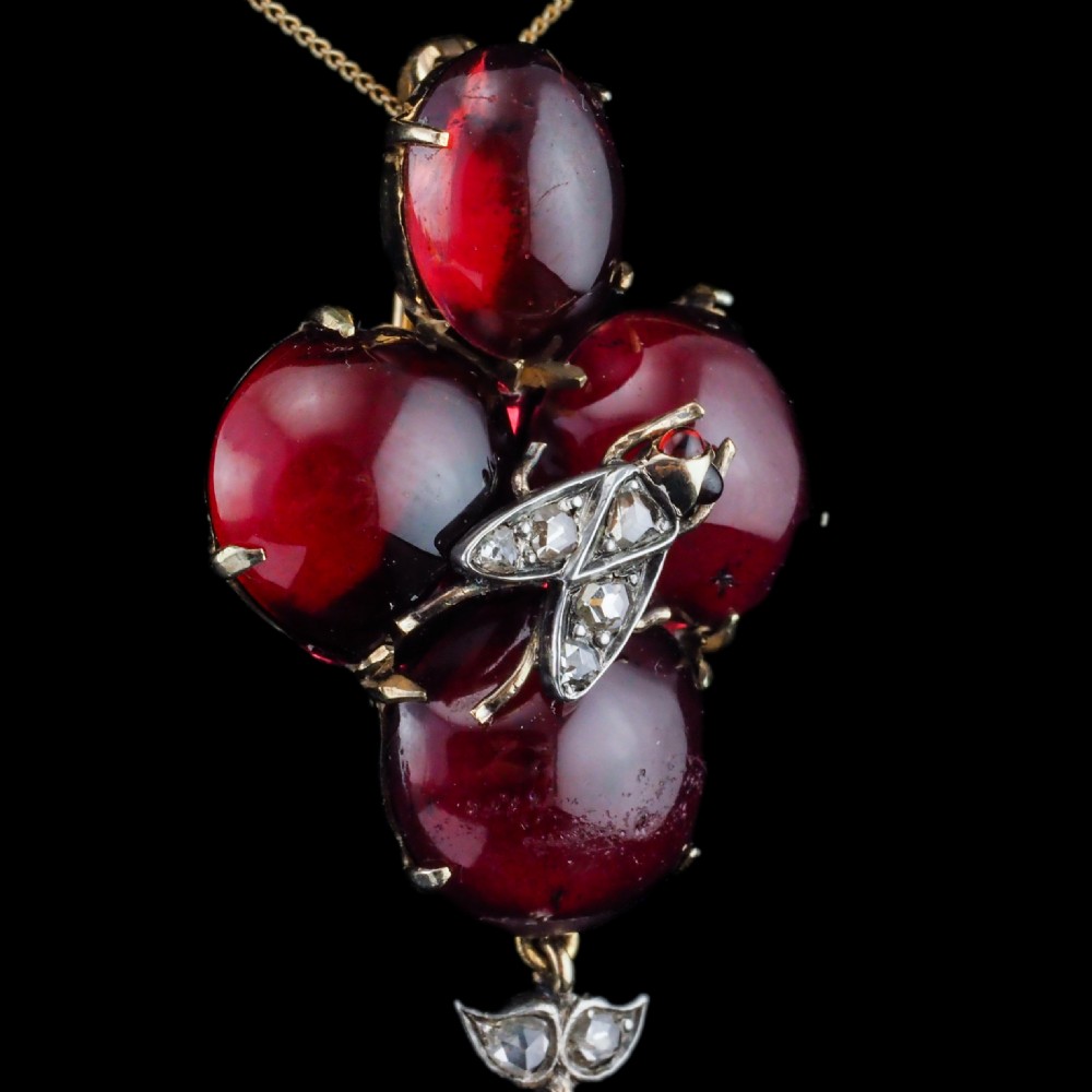 Victorian gold brooch pendant set with four deep red cabochon garnets, a diamond-encrusted insect motif at the centre, and an articulated diamond drop. View VII
