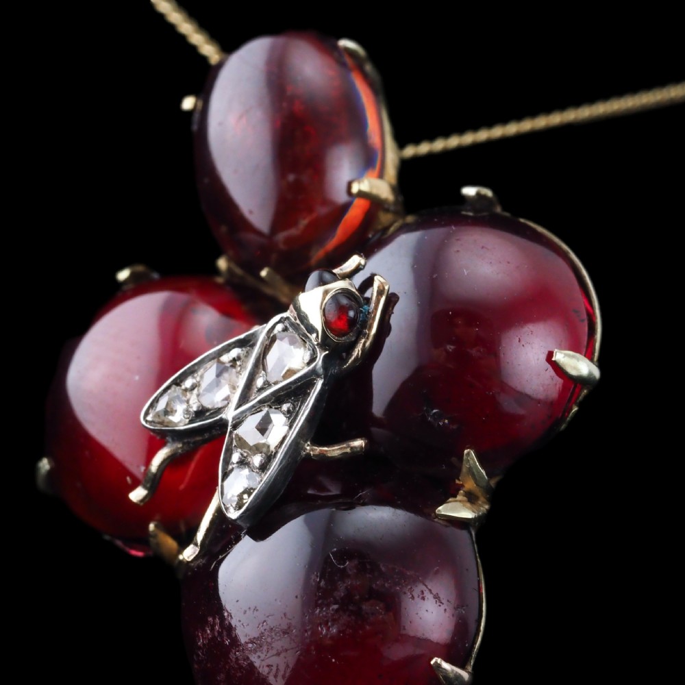 Victorian gold brooch pendant set with four deep red cabochon garnets, a diamond-encrusted insect motif at the centre, and an articulated diamond drop. View X