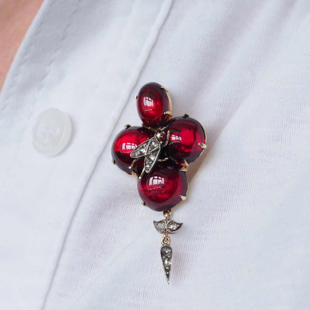 Victorian gold brooch pendant set with four deep red cabochon garnets, a diamond-encrusted insect motif at the centre, and an articulated diamond drop. View XV
