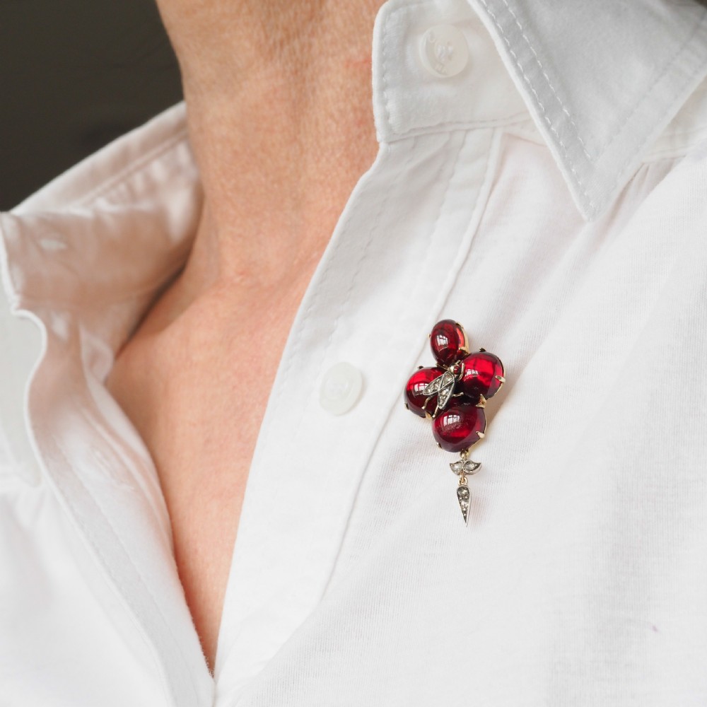 Victorian gold brooch pendant set with four deep red cabochon garnets, a diamond-encrusted insect motif at the centre, and an articulated diamond drop. View XVI