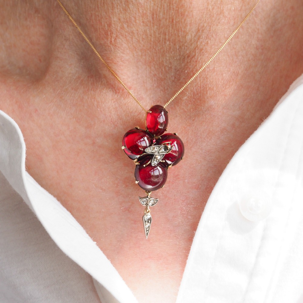 Victorian gold brooch pendant set with four deep red cabochon garnets, a diamond-encrusted insect motif at the centre, and an articulated diamond drop. View XVIII