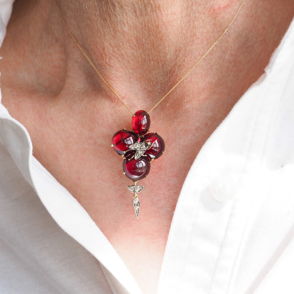 Victorian gold brooch pendant set with four deep red cabochon garnets, a diamond-encrusted insect motif at the centre, and an articulated diamond drop. View XIX