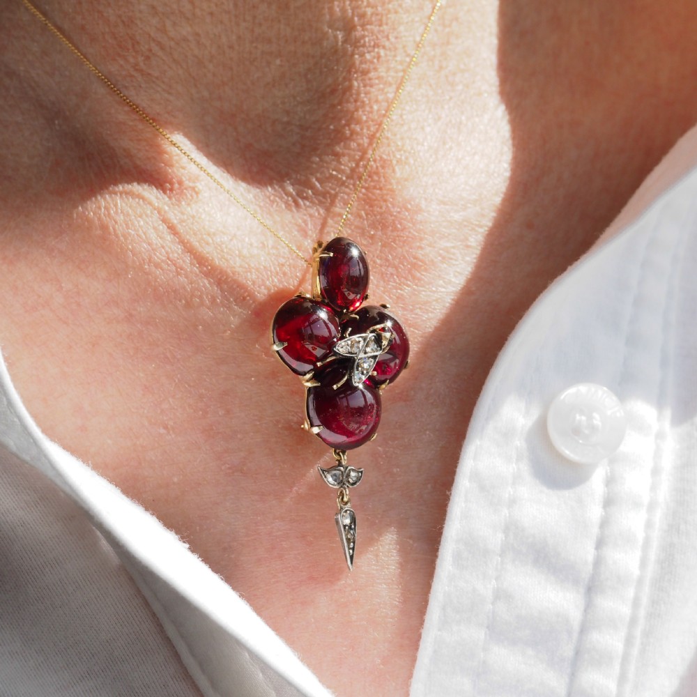 Victorian gold brooch pendant set with four deep red cabochon garnets, a diamond-encrusted insect motif at the centre, and an articulated diamond drop. View XX