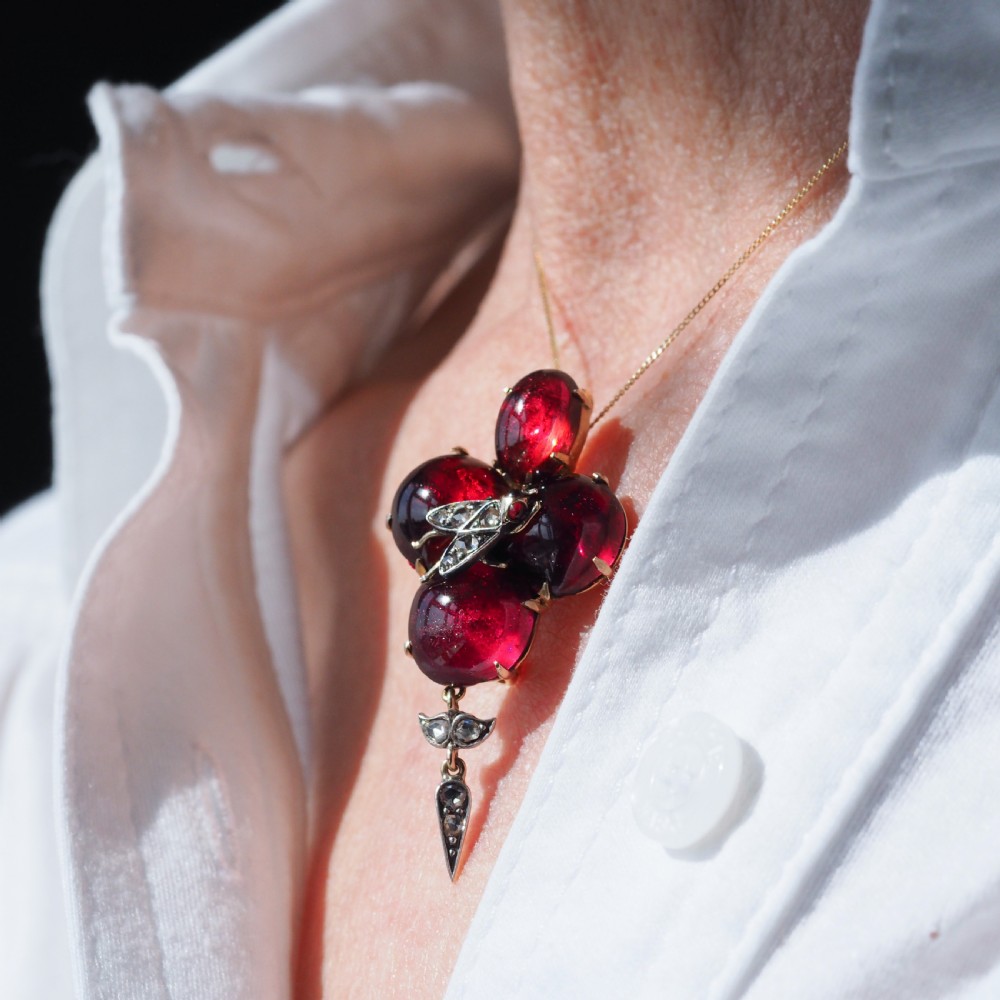 Victorian gold brooch pendant set with four deep red cabochon garnets, a diamond-encrusted insect motif at the centre, and an articulated diamond drop. View XXI