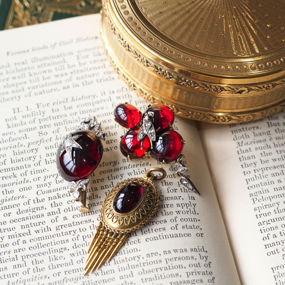 Victorian gold brooch pendant set with four deep red cabochon garnets, a diamond-encrusted insect motif at the centre, and an articulated diamond drop. View XXVI