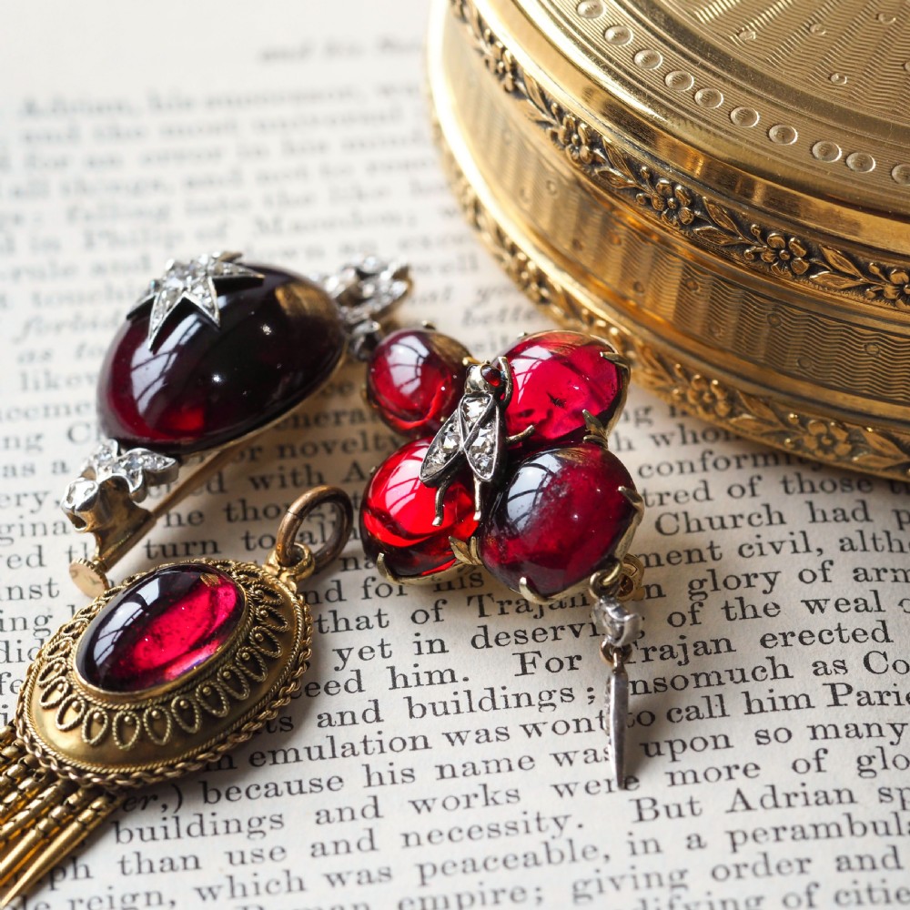 Victorian gold brooch pendant set with four deep red cabochon garnets, a diamond-encrusted insect motif at the centre, and an articulated diamond drop. View XXVII