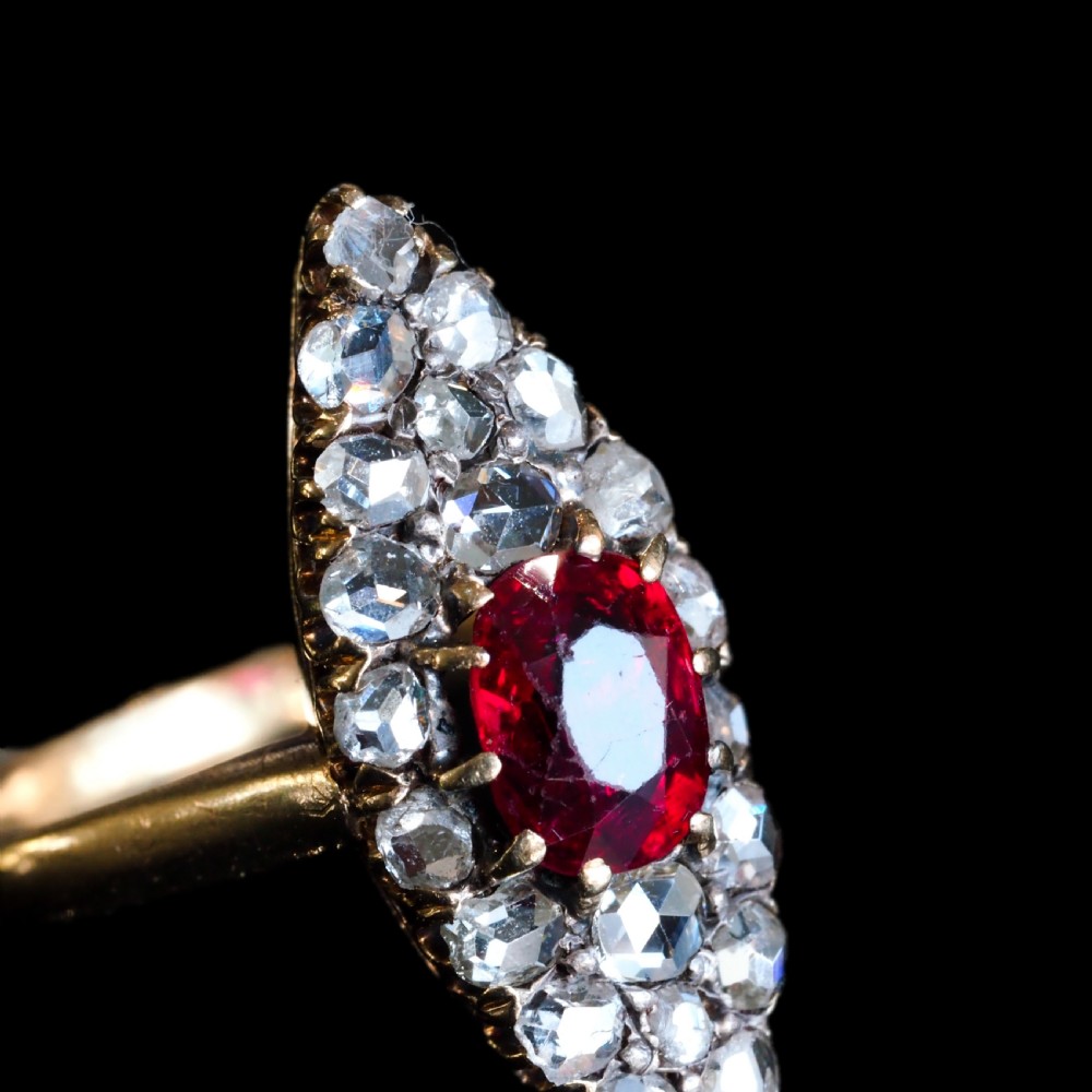 An antique late-nineteenth-century French 18k gold navette cluster ring featuring a central oval red ruby surrounded by multiple rose-cut diamonds. View X