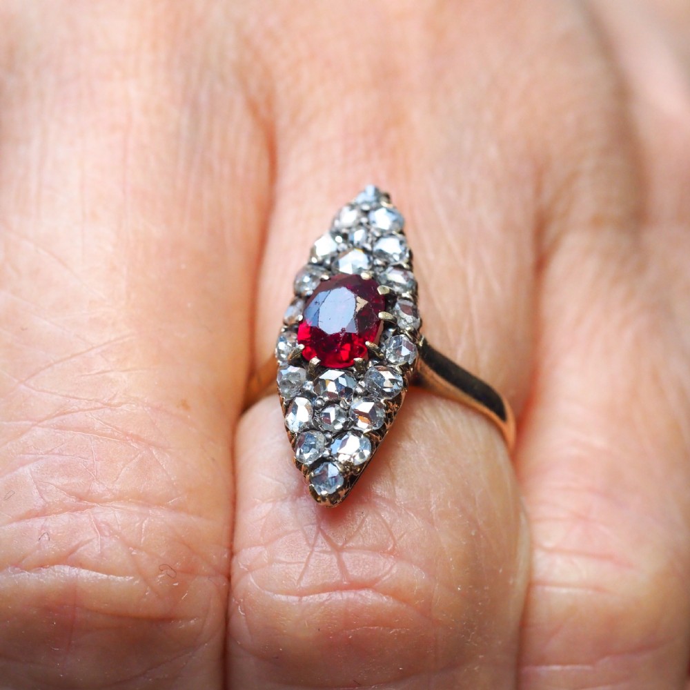 An antique late-nineteenth-century French 18k gold navette cluster ring featuring a central oval red ruby surrounded by multiple rose-cut diamonds. View XII