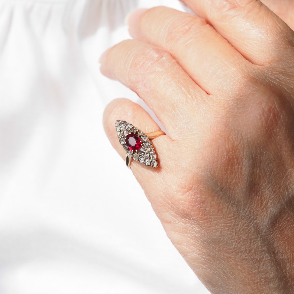 An antique late-nineteenth-century French 18k gold navette cluster ring featuring a central oval red ruby surrounded by multiple rose-cut diamonds. View XVI